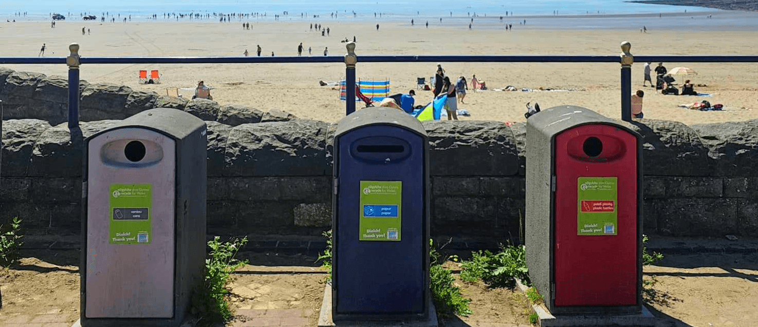 3 recycling bins in a line against the backdrop of Barry Island beach