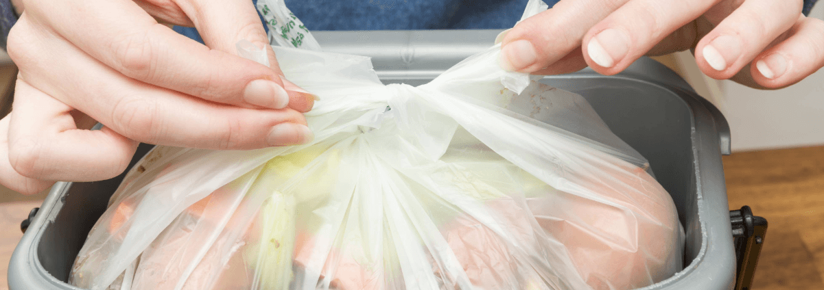 Hands tying a food caddy liner in a food caddy